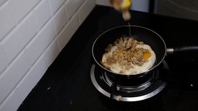 Asian chef fried eggs on pan to thai food in kitchen on gas stove The oil in pan boiling.Eggs and pork cooked. before serving to happy family to eat video for slowmotion