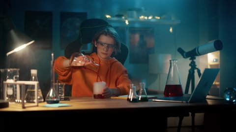 Smart Young Boy in Safety Goggles Mixes Colorful Chemicals in Beakers at Home. Teenager Conducting Educational Science Hobby Experiments, Doing Interesting Biology Homework in His Room.