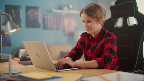 Smart Young Boy in Checkered Shirt Using Laptop Computer in Cozy Room at Home. Happy Teenager Browsing Educational Research Online, Chatting with Friends, Studying School Homework.