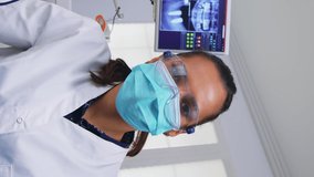 Vertical video: Pov of dentist working on patient mouth hygine in dental office checking teeth problems. Doctor examining in orthodontic office with light lamp and sterilized utensils, close-up face