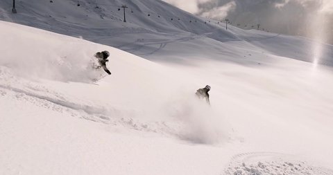 Cinematic downhill freeride skiing of two professional ski mountain guides in fresh deep snow with amazing mountain landscape. Freeride athletes showing off piste ski turns with awesome panorama view