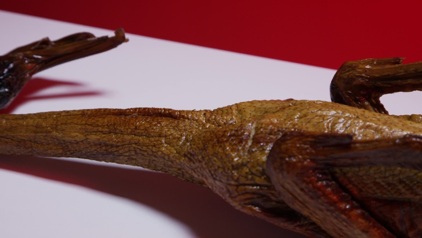 Full smoked duck on a white surface with a red background. 