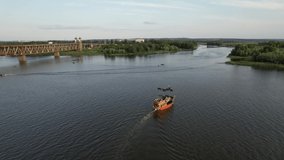 Sailing ship sails on the calm waters along the river bank in sunny weather: Beautiful 4K panoramic aerial video from flying drone