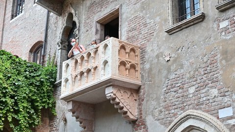 Verona, Italy, June 2021. The legendary balcony of Juliet, tradition attributes the narration of Shakespeare to this balcony. Visitors look out curiously.
