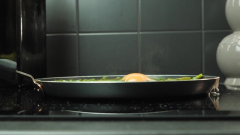Breaking egg into pan. Man hand breaks egg in frying pan with green beans. Cooking process of tasty healthy food