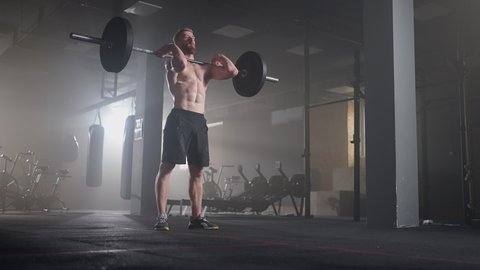 Slow motion of crossfit athlete performs clean and jerk. Young man doing the clean and jerk weightlifting exercise at the gym.