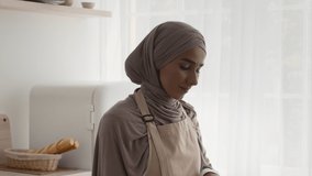 Muslim Housewife Cooking Cutting Fresh Vegetables For Salad Standing In Modern Kitchen At Home, Wearing Hijab. Middle-Eastern Lady Preparing Dinner Indoor. Healthy Nutrition Concept. Tracking Shot