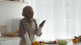 Muslim Blogger Woman Taking Photo Of Food While Cooking Standing In Modern Kitchen At Home, Wearing Hijab. People And Gadgets Concept. Tracking Shot, Slow Motion