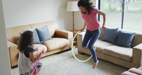 Mixed race mother and daughter playing with hula hoops. domestic life and family leisure time concept.