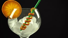 Pouring gin orange cocktail in large glass with ice, 4k vertical video, close up