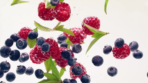 Raspberry, blueberry, mint leaves splash floating in the water, white background