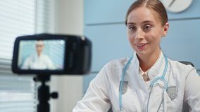 Young woman blonde medical blogger in white coat talks