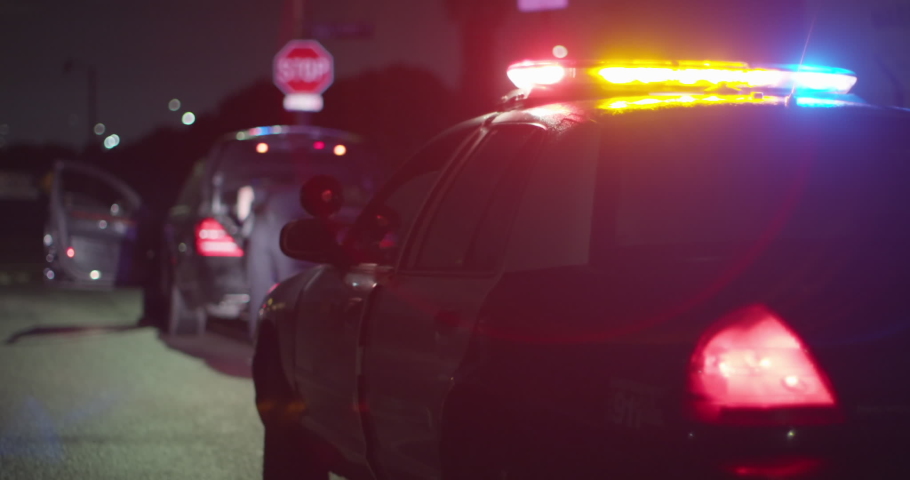 Police Officer Searches Trunk Of Suspect At Night. Flashing Police Lights, Female Officer, Slow Motion, Police Stop, Pulled Over