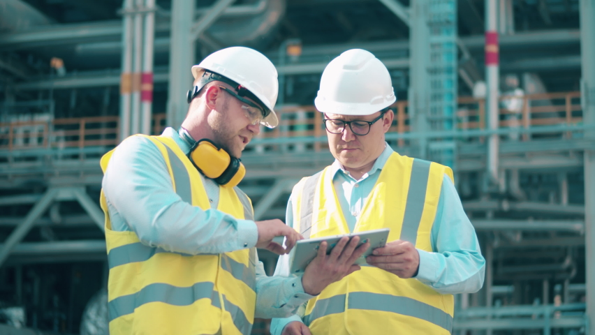 Oil industry, petrochemical factory, refinery concept. Engineers in hardhats are talking at the oil refinery | Shutterstock HD Video #1075519868
