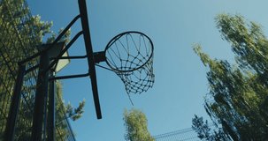 Basketball court on nature. Ball throwed into basketball hoop flies past on summer sky background. Aiming, goal concept