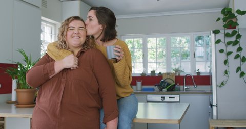 Caucasian lesbian couple embracing and drinking coffee. domestic life, spending free time relaxing at home. Video Stok