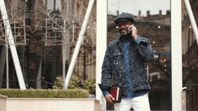 Stylish African American guy talking by phone outdoors