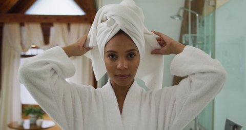 Portrait of mixed race woman wearing bathrobe looking at camera. domestic life, spending quality free time relaxing at home.