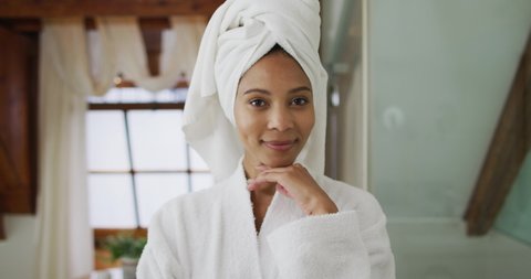 Portrait of mixed race woman wearing bathrobe looking at camera. domestic life, spending quality free time relaxing at home.