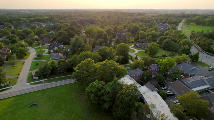 Overhead flyover nice houses in upscale neighborhood in Town and Country in St. Louis, Missouri at sunset.