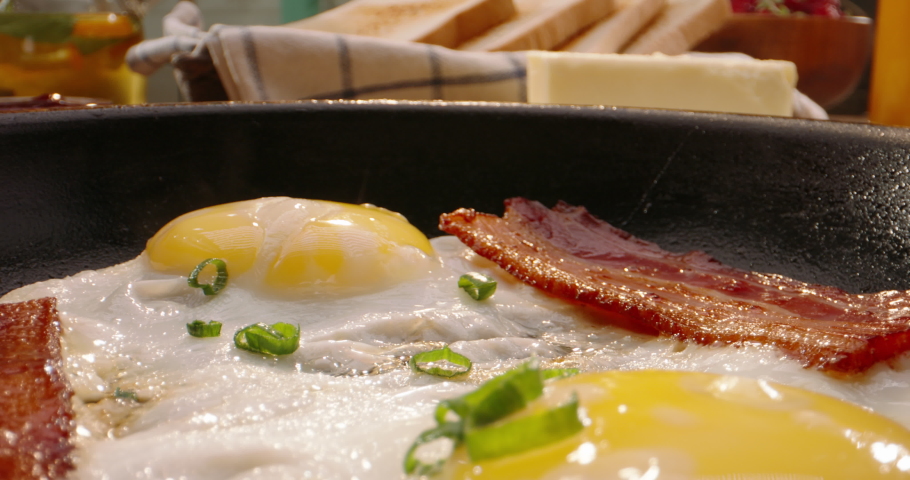 Putting frying pan with freshly fried eggs and bacon on table with served nourishing balanced breakfast - morning meal preparation 4k footage Royalty-Free Stock Footage #1075532441