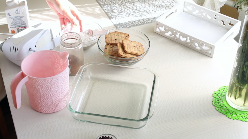 The woman is making ice cream. There are ingredients for cooking on the table