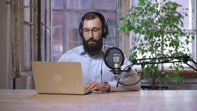 Man radio host recording podcast with laptop at home. bearded man look at computer screen