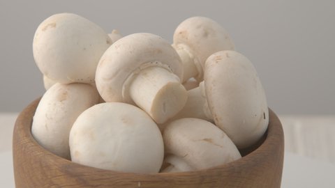 young champignon mushrooms rotate in a deoevyan plate. Eco products for a healthy life. Raw mushrooms on plate. close-up. champignon on plate.