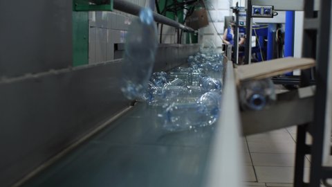 Empty plastic bottles fall on the conveyor belt. Plant for the production of drinking and mineral water