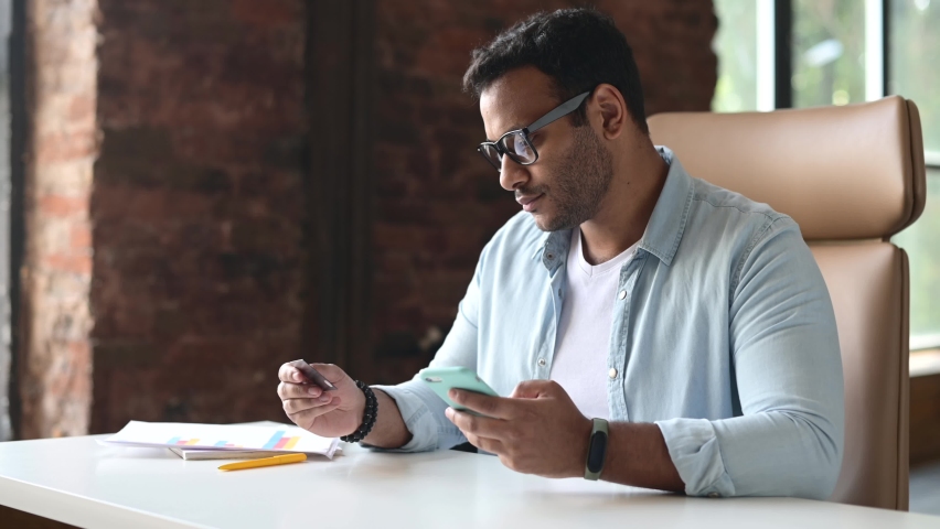 Smilimg indian guy holding credit card and smartphone transferring money online, making online transaction, checking banking account online, using mobile app for e-banking Royalty-Free Stock Footage #1075553987