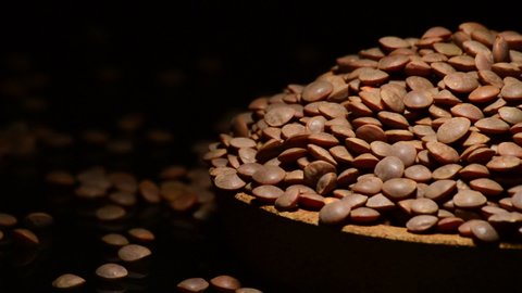 Mountain of lentils legume on a plate gyrating on black background