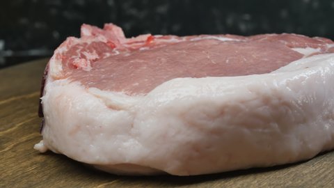 The cook puts green sprigs of dill on the fresh pork meat with a fat-edged pink entrecote. Dolly shot. Close-up