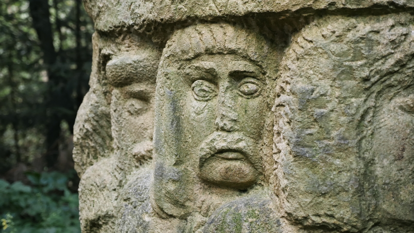 Carved sculpture of human faces in stone in the Carpathian forest