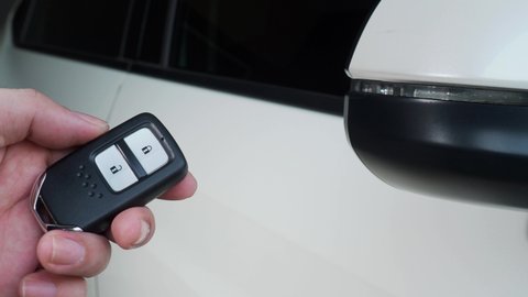 Car key remote control. Locking and unlocking the car by the car key remote control. Pressing the button of the car key and the lights blink when door open or closed. Man hand using remote key.