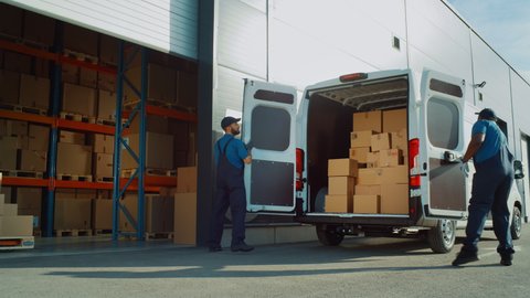 Outside of Logistics Distributions Warehouse: Two Workers Load Delivery Truck with Cardboard Boxes, Drive Off to Deliver Online Orders, Purchases, E-Commerce Goods. Wide Shot