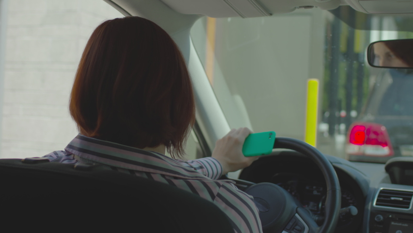 30s female driver paying bill with mobile phone and contactless terminal sitting in the car. Woman using NFC payment on her cellphone to pay for fast food restaurant. Taking away food from car. Royalty-Free Stock Footage #1075563467