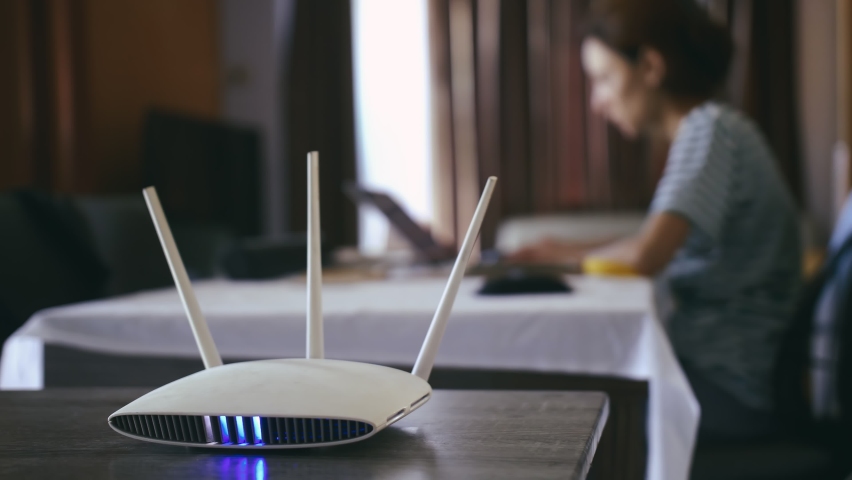 A woman is working at home using a modem router, connecting the internet to her laptop. Royalty-Free Stock Footage #1075566200