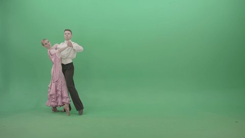 Luxury ballroom foxtrot dance by young couple 4K Video Footage. Pretty couple of classic ball dancers performing waltz moves on green background. Dancers in luxury costumes on green screen
