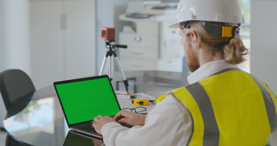 Over shoulder shot of civil construction engineer working with laptop at desk in office. Industrial engineer typing on computer in modern office. Green screen Royalty-Free Stock Footage #1075566623