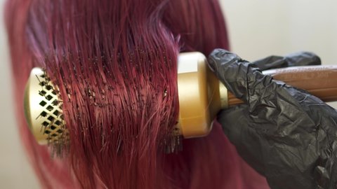 Hair dryer closeup. beauty salon female stylist. Dyed hair pink. Dry hair style hair. Woman in black gloves work with girl head care. pro is learn make volume and curls. round comb dryer attachment