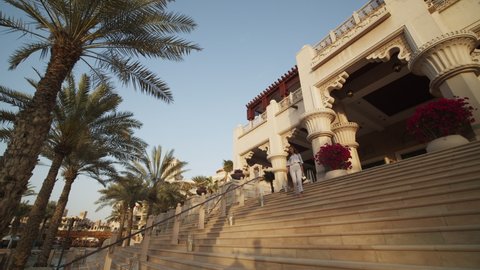 Woman walking down the stairs in front of luxury house in Dubai. Front view of woman walking in rich luxurious neighborhood in United Arab Emirates