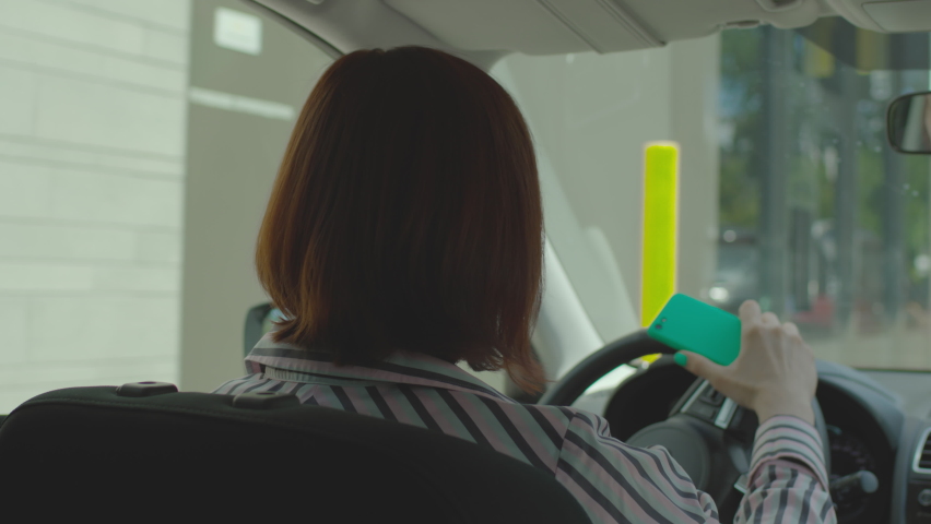 Young adult driver ordering fast food, paying bill with mobile phone and contactless terminal sitting in the car. Woman using NFC payment on her cellphone at fast food driving restaurant. Royalty-Free Stock Footage #1075572812
