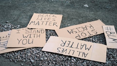 Paper banners with inscriptions BL, ALL LIVESMATTER, STOP RACISM lie on the ground. 
