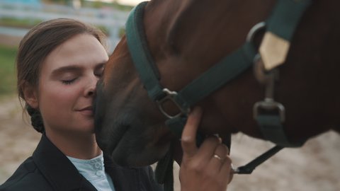 Horsewoman touching her face to her seal brown horse. The girl is smiling and showering love on her horse. bonding between horse and human being. Daytime footage. 