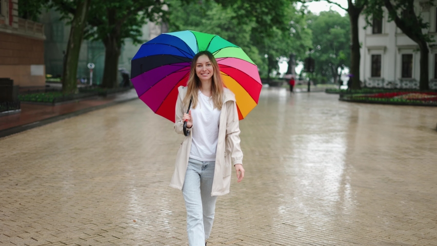 Portrait of a woman walking by city street with multi-colored umbrella
