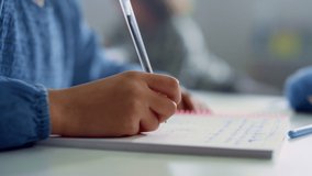 Closeup african american girl writing in notebook at school desk. Afro schoolgirl hand making notes in exercise book at lesson. Child arm using pen. Female student doing classwork at school - Powered by Shutterstock - Get 15% off with code: PIKWIZARD15
