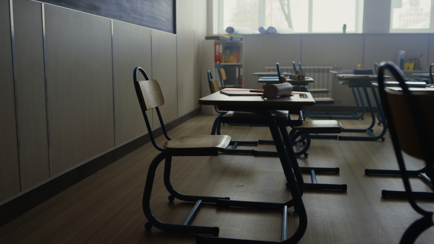 Camera moving in empty school room. Interior of empty classroom with wooden desks and chairs for education. Modern class in school campus. School supplies lying on tables  Royalty-Free Stock Footage #1075580534
