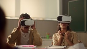Excited kids in vr glasses learning in modern school. Positive classmates wearing virtual reality headsets during interactive lesson in classroom. Mixed race children immersing in virtual reality - Powered by Shutterstock - Get 15% off with code: PIKWIZARD15