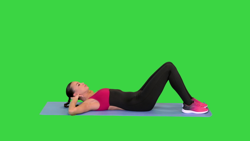Beautiful sporty woman doing exercise for abs on the floor on a Green Screen, Chroma Key.