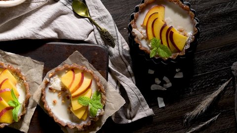 Peach vegan tarts with grated coconut  and crunchy peanuts. Fruit cake. Date, walnut, almond and hazelnut base.